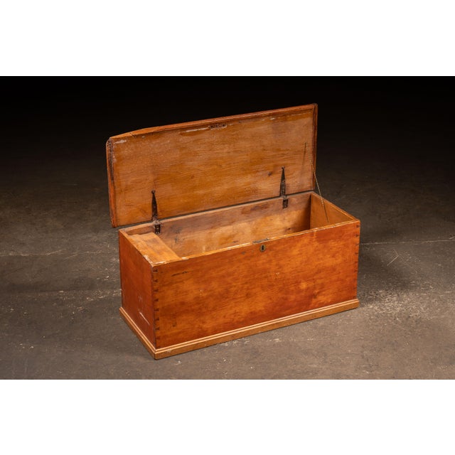 Rectangular wooden blanket chest constructed with hand-cut dovetail joinery at the case corners and an original iron strap...