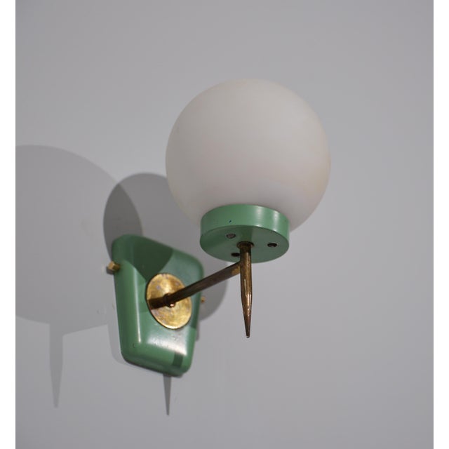This wall-mounted sconce exemplifies Italian design from the 1950s, featuring a minimalist yet functional aesthetic. The...