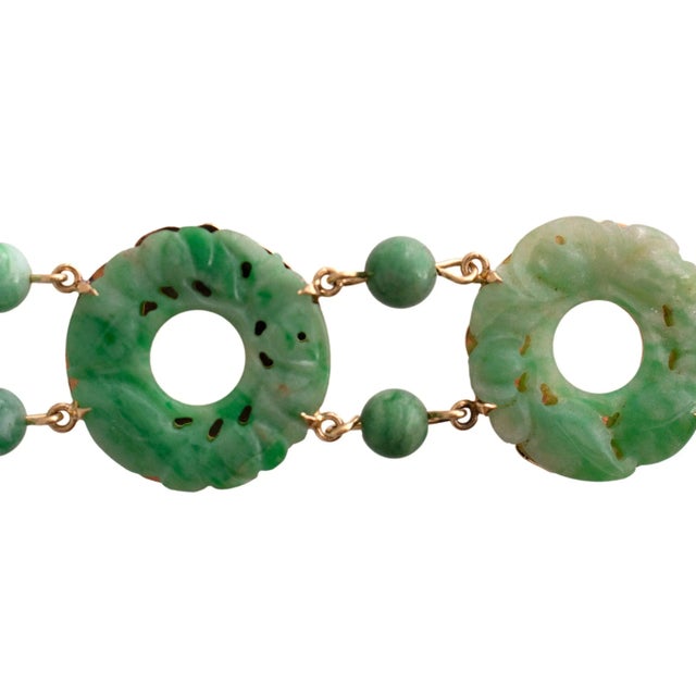 Jade link bracelet features a series of intricately carved jade discs, each connected by small jade beads. The bracelet is...