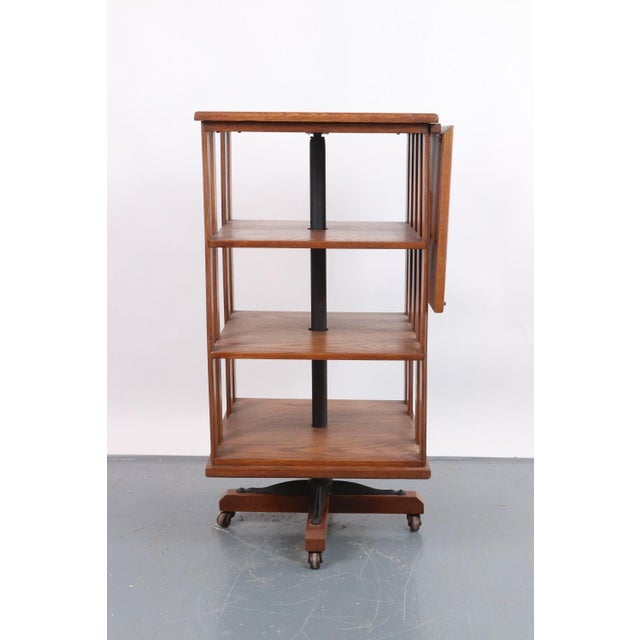 Spinning side table bookcase with an adjustable reading stand in medium toned wood. Streamlined geometric design and an...