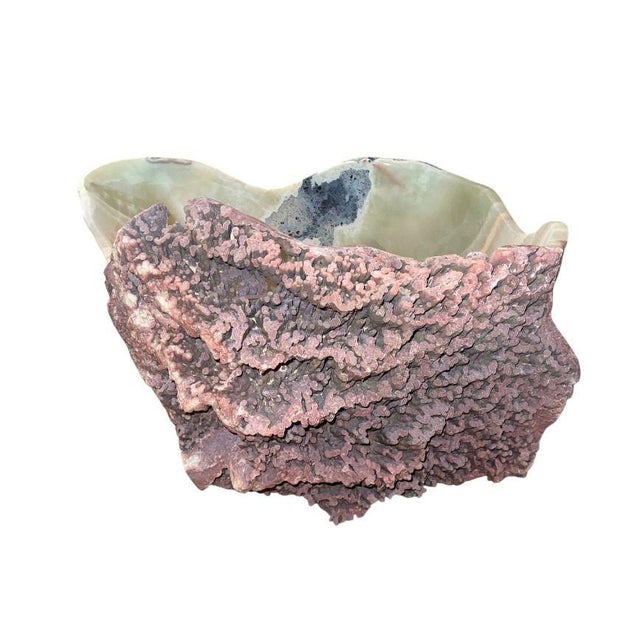 A monumental carved onyx bowl featuring dramatic natural mineral formations and richly banded coloration. The interior is...