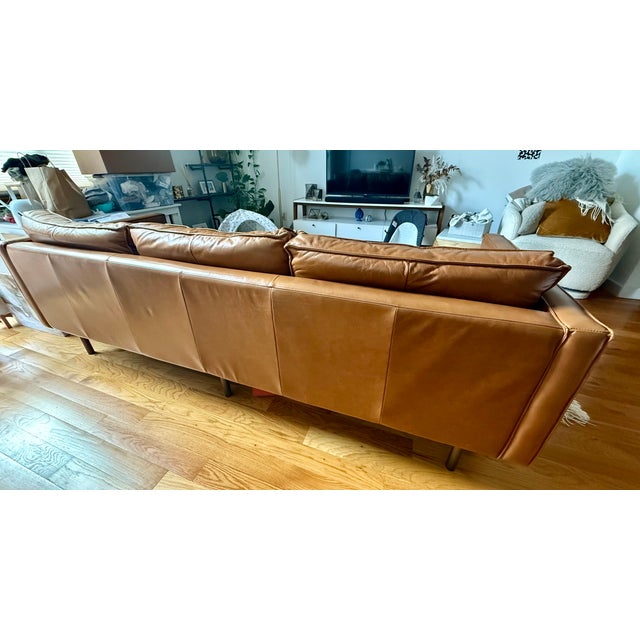 A West Elm Axel 89” sofa in warm brown top-grain leather, featuring a clean-lined, low-profile silhouette inspired by mid-...