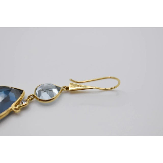 This is a gorgeous pair of blue topaz and diamond drop earrings et in 18K yellow gold. They feature pear cut topaz with a...