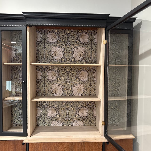 Beautiful vintage breakfront. Has black and wood tones with cool rope trim. Inside, there's decorative wallpaper lining...
