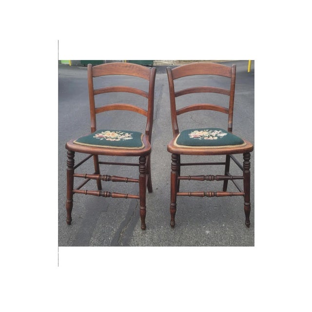 A pair of early 20th century Victorian style ladder back walnut and Needlepoint upholstered seat side chairs in very good...