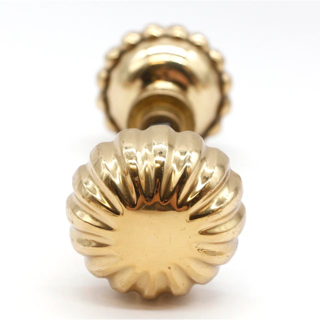 Vintage brass fluted shaped door knobs featuring a polished finish. Good functional condition with surface wear from prior...