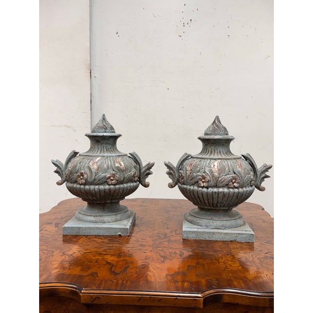 Design Plus Gallery presents a Pair of Neoclassical Style Decorative Faux Urns. Each urn has a silhouette with a pointed...