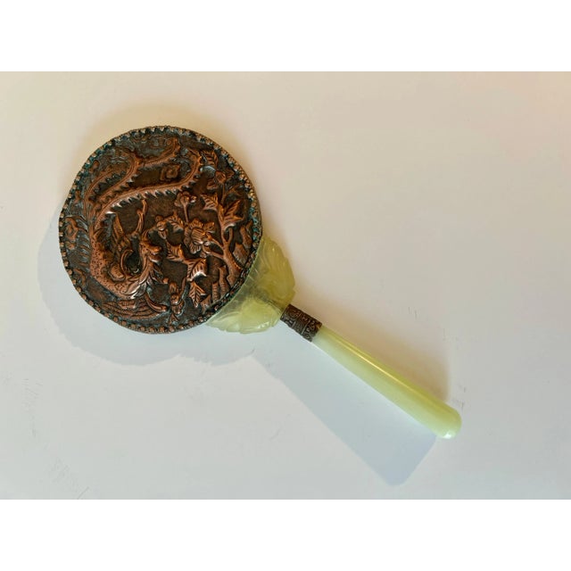 A beautiful hand mirror with repousse Dragon and scene. Filagree surround cradled by jade and Celadon Handle. A wonderful...