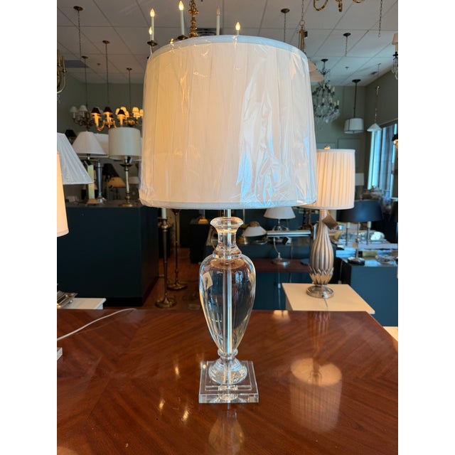 A solid crystal urn table lamp from Haig featuring a faceted urn-form body and a clear crystal square base. The elegant...