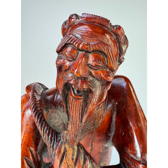 A charismatic mid-century Chinese hand-carved hardwood figure of an elderly fisherman carrying a large fish over his...