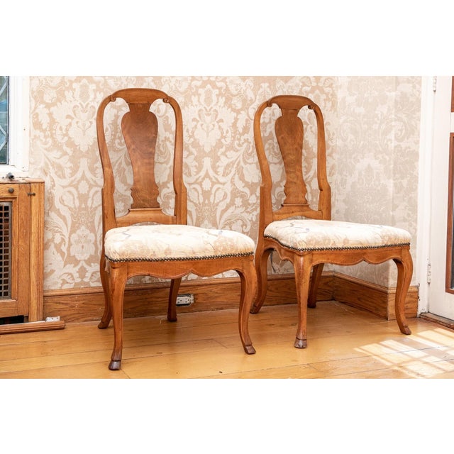 A pair of 18th century Queen Anne style upholstered walnut carved side chairs with a baluster form back splat, scrolled...