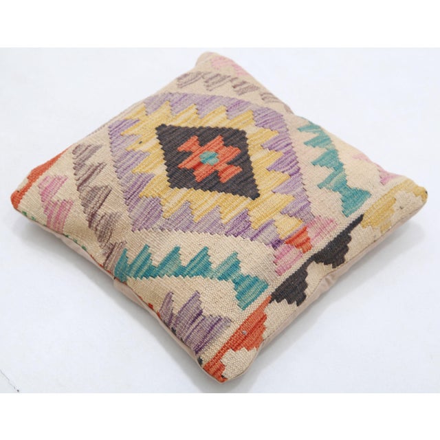 A one-of-a-kind handwoven Afghan wool kilim accent pillow featuring central diamond medallion on a pastel zigzag field....