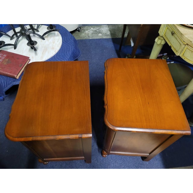 A fine pair of French three drawer nightstands in sold cherry wood. Each have shaped fronts, brass pulls and clean like...