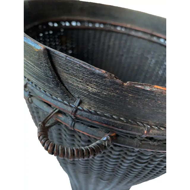 This mid-20th century hand-woven basket originates from the Dayak tribe of Borneo crafted with rattan fibres and an...