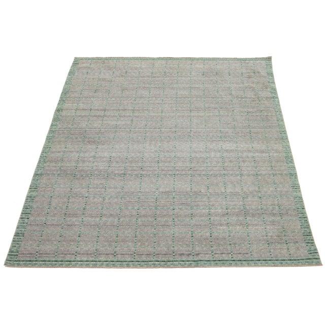 This hand-loomed modern wool rug is designed to captivate. Its elegant light gray background is a perfect canvas for the...