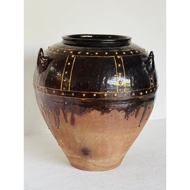 A large, heavy earthenware jar with brown glaze. The traditional Martaban form decorated with three frog figures applied...