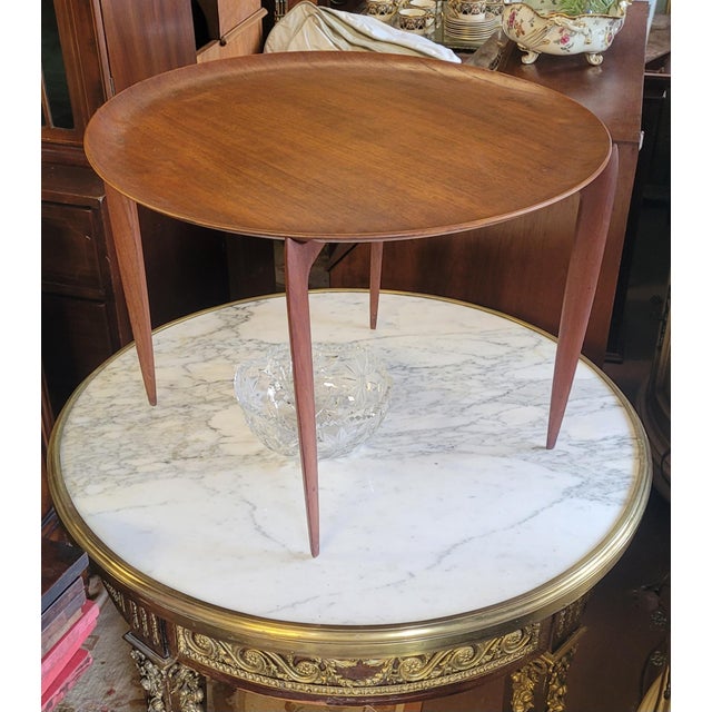 Rare Fritz Hansen Danish teak small disc table. Features a disc top with curved up edge, folding base in teak wood....