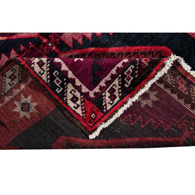 A hand-knotted vintage Azeri runner with an artistic design on a burgundy field. Multi-color accents throughout the piece....