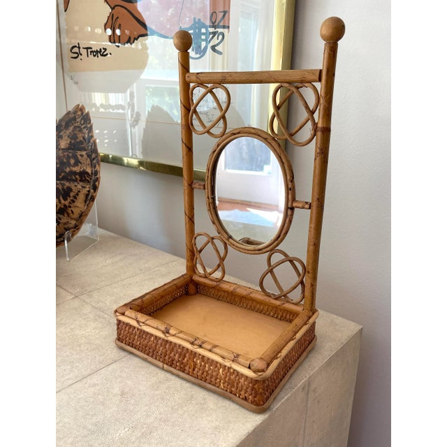 Vintage Tortoise Rattan tabletop mirror with bottom holder. sides wrapped with woven rattan. Oval center mirror measures...