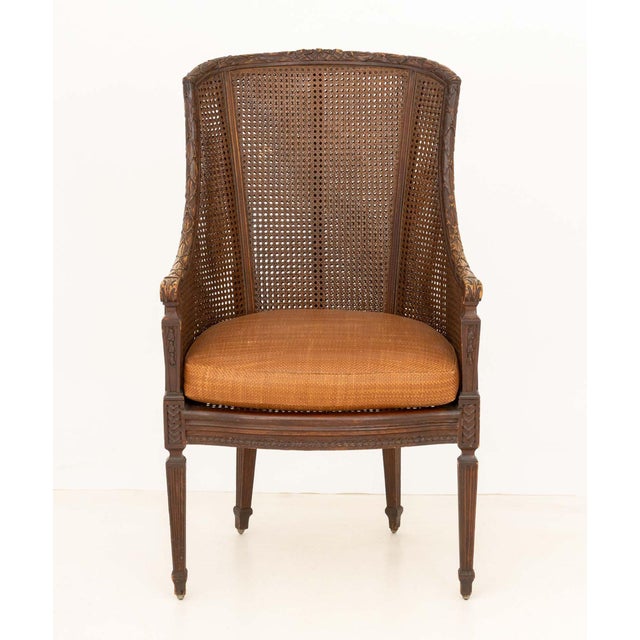 American Regency Style Floral Carved Mahogany Cane Paneled Bergere, with woven leather cushion on four tapered legs....
