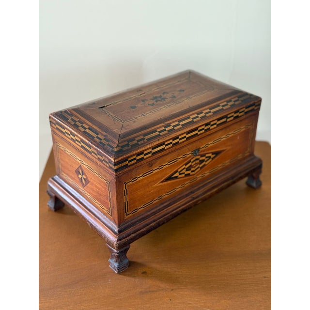 This is a 19th century inlaid marquetry jewelry box with striking geometric pattern, perched on four carved cabriole legs....