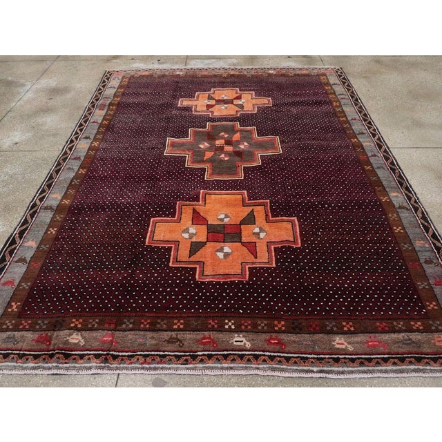 This mid-20th century Turkish Anatolian tribal carpet, measuring 7' 9" x 10' 0", presents a striking composition that...