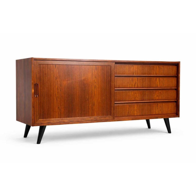 A compact 160 cm Danish teak sideboard from the 1960s with sliding doors and drawers. The diagonally tapered legs maintain...