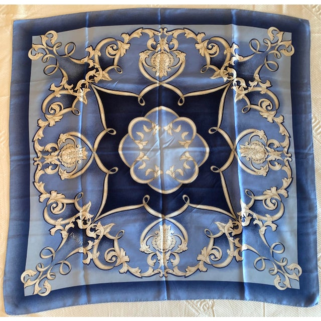 Elegant Escada silk scarf featuring a sophisticated blue gradient background and ornate white baroque scrollwork