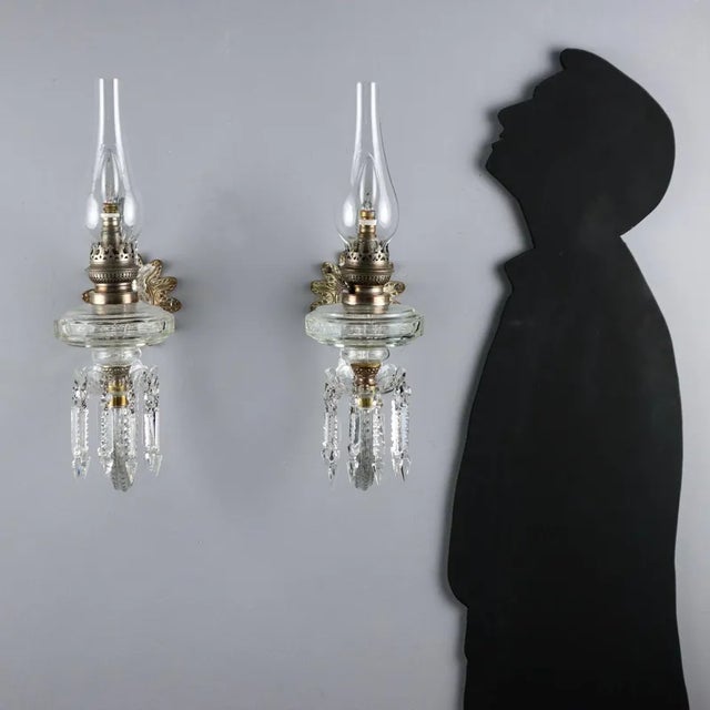 Pair of crystal wall lamps, made with fake oil lantern light, glass bobeches and pendants. Italy, 20th century. This piece...