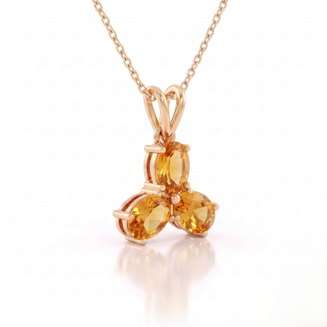 A radiant three-stone design featuring oval-cut natural citrines arranged in a graceful trefoil formation, secured in a...
