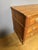 An 18th-century Louis XVI commode in light walnut. It features three drawers in the front, separated by crossbars, and...