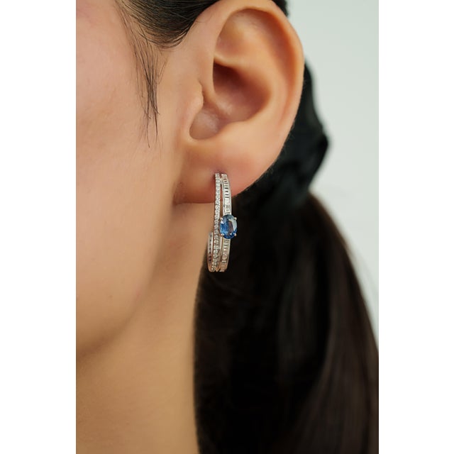 These hoop earrings feature 1.23 carats of oval blue sapphires set in 14K white gold. The sapphire measuring 4.2 x 6 mm,...