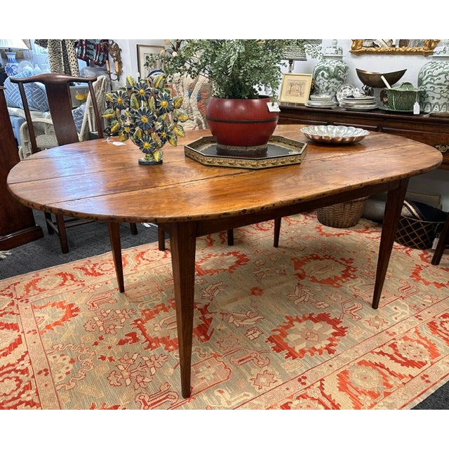 An exceptional antique country harvest style oval dining table crafted from solid wood. Featuring a four plank Top in a...