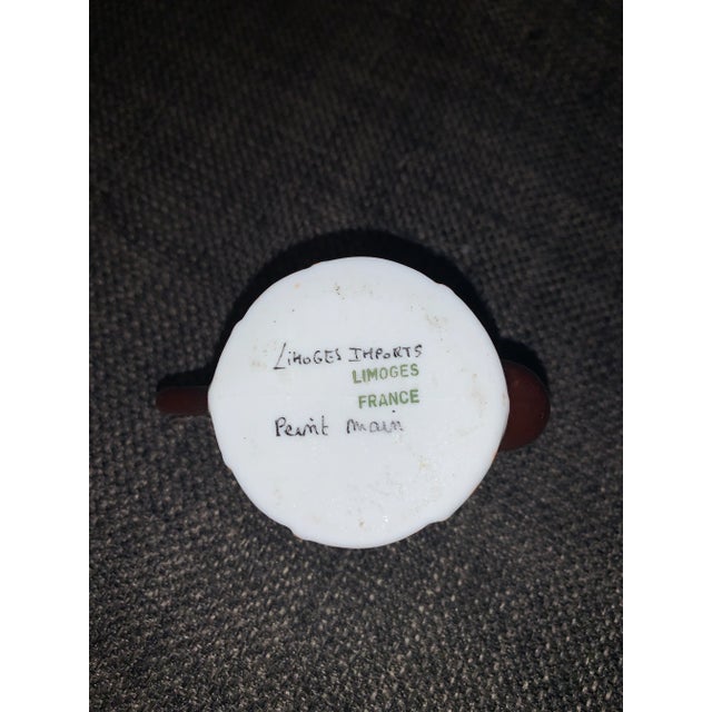 Hand-painted porcelain trinket box shaped like a teapot with a fruit design on the lid. The Vintage box has a brass trim...