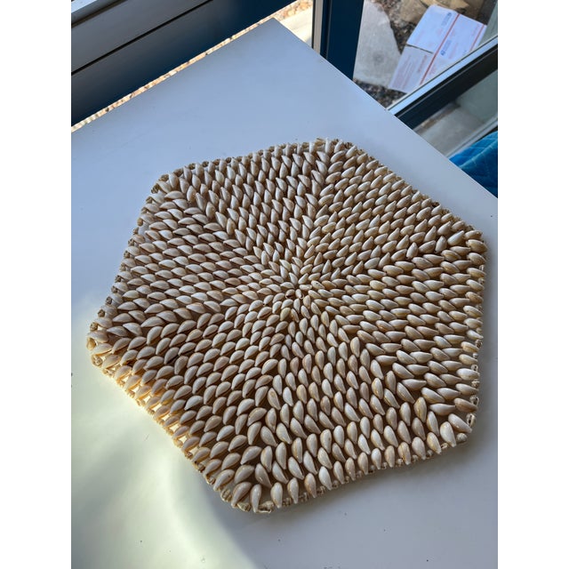 Pair vintage cowrie shell placemats or trivets. Measuring 14" x 12" in a hexagonal shape. One is missing one shell as...