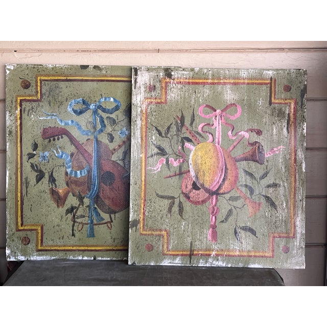 A pair of antique decorative oil on wood painting panels executed in the Neoclassical Style. Originally designed as...