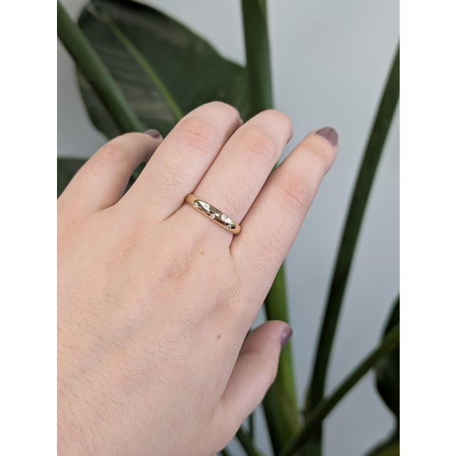 A modern take on a classic symbol, this women's wedding band is crafted in solid 14k yellow gold with flush-set natural...