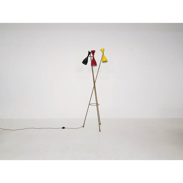 Tripod floor lamp in the style of the "Triennale" floor lamp by Arredoluce. The floor lamp is made of brass stems forming...