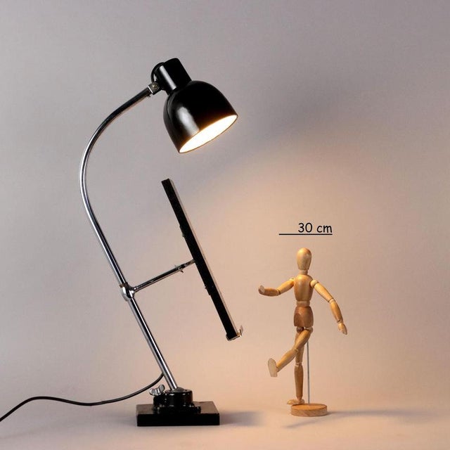 Table lamp with small lectern on the stem. Chromed metal, enameled aluminum and wood. This piece is attributed to the...