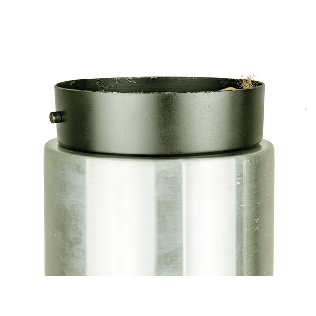 This cylindrical ceiling lamp is made from a silver and black painted aluminum body with a white sandblasted glass shade....