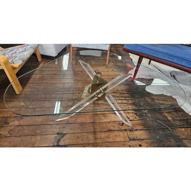 Sculptural Mid-Century Modern coffee table with lucite and brass 'JAX' style tripod base with glass top. Circa 1970s....