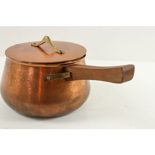 This Danish modern copper sauce pan was designed in the style of Jens Quistgaard with modern curved brass handles in the...