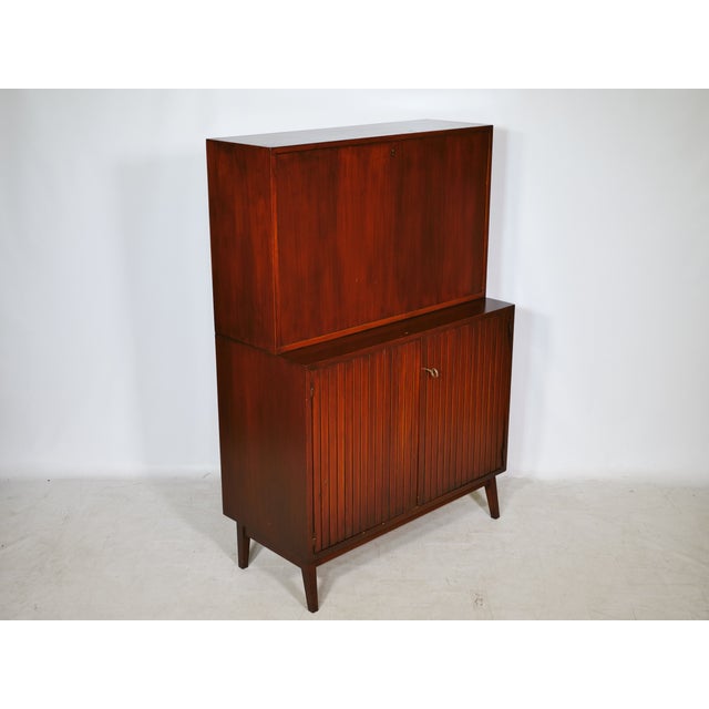 Mid-century teak bar cabinet, 1960s. Compact cabinet with a vertically divided front, a bar top, and slender tapered legs....