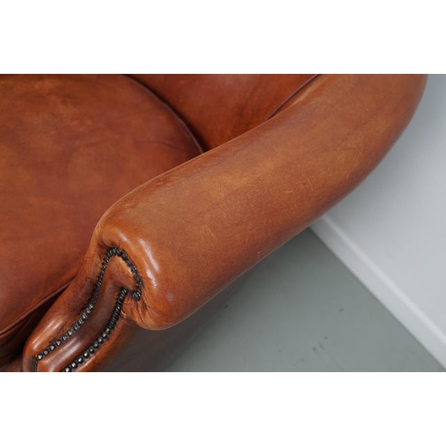 This pair of cognac-colored leather club chairs come from the Netherlands. They are upholstered with patinated cognac-...