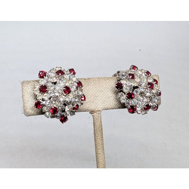 1960s rhodium plated round clear rhinestone with round faux-garnet accents clip earrings. Marked "©Vendôme" on the clips....