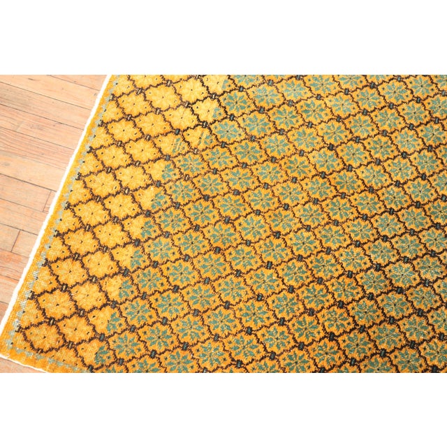 A mid-20th century Turkish rug with an all-over repetitive floral motif in green and brown on saffron field Measures:...