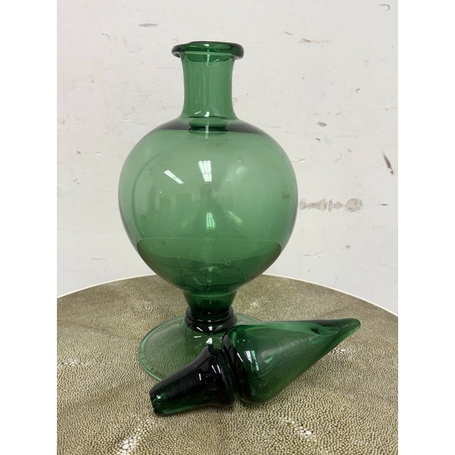 Design Plus Gallery presents a Green Toned Hand Blown Vessel from Italy. The green glass decorative bottle has a rounded...