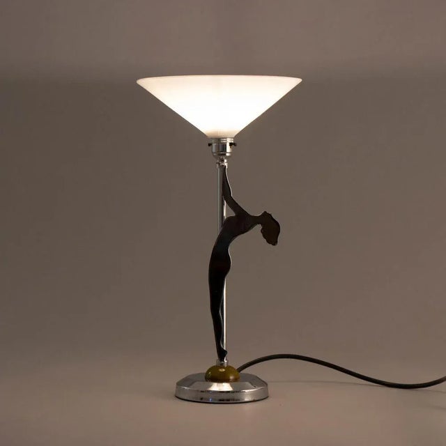 H: 44.5cm w: 23cm d: 23cm an art deco chrome table lamp with a silhouette nude raised on a green phenolic and chrome base....