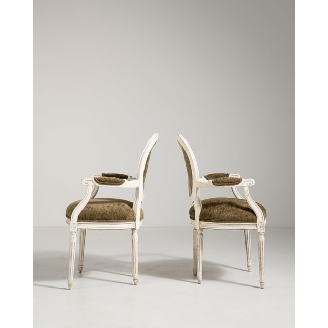 A refined pair of Louis XVI armchairs characterized by clean, straight lines and neoclassical symmetry. The upholstered...