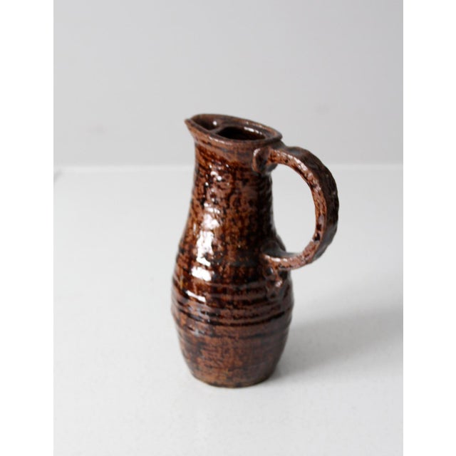 Handmade studio pottery pitcher dated 1975 and signed E. Denu Cowen. Thrown in stoneware with a softly tapered form,...